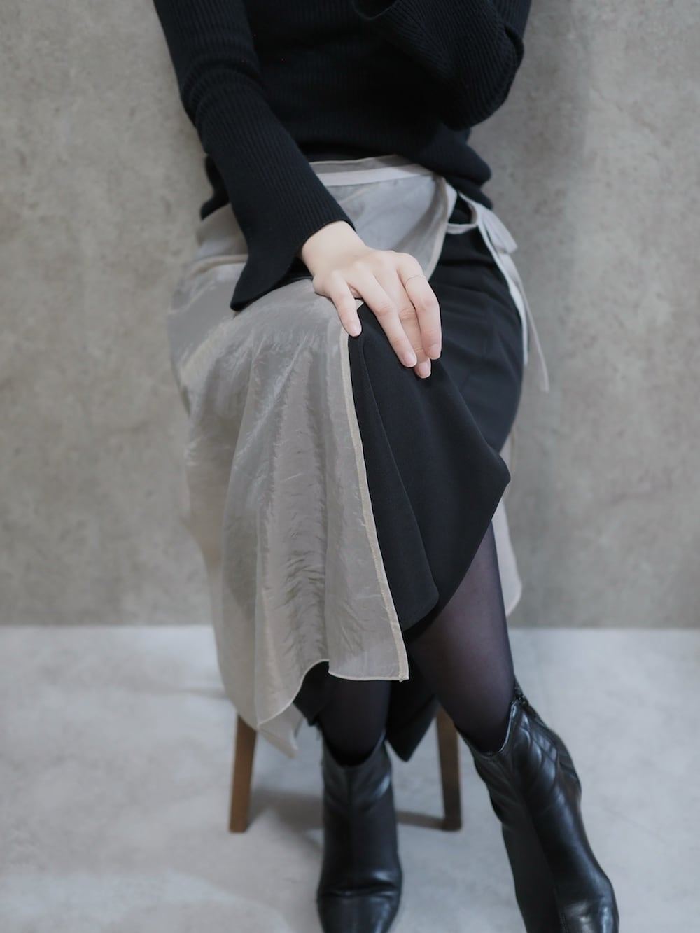 ブラック系のニット/セーター、ベージュ系のスカート、ブラック系のブーツを着用したレディースの冬コーディネートの2枚目の写真