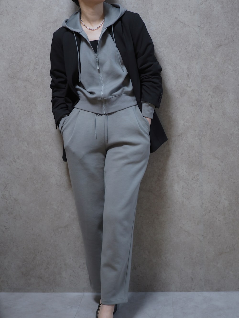 グレー系のパーカー、ブラック系のテーラードジャケット、グレー系のスウェットパンツを着用したレディースの春コーディネートの2枚目の写真