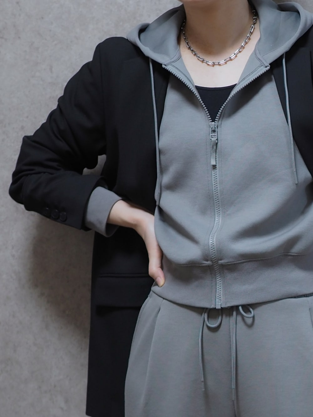 グレー系のパーカー、ブラック系のテーラードジャケット、グレー系のスウェットパンツを着用したレディースの春コーディネートの3枚目の写真