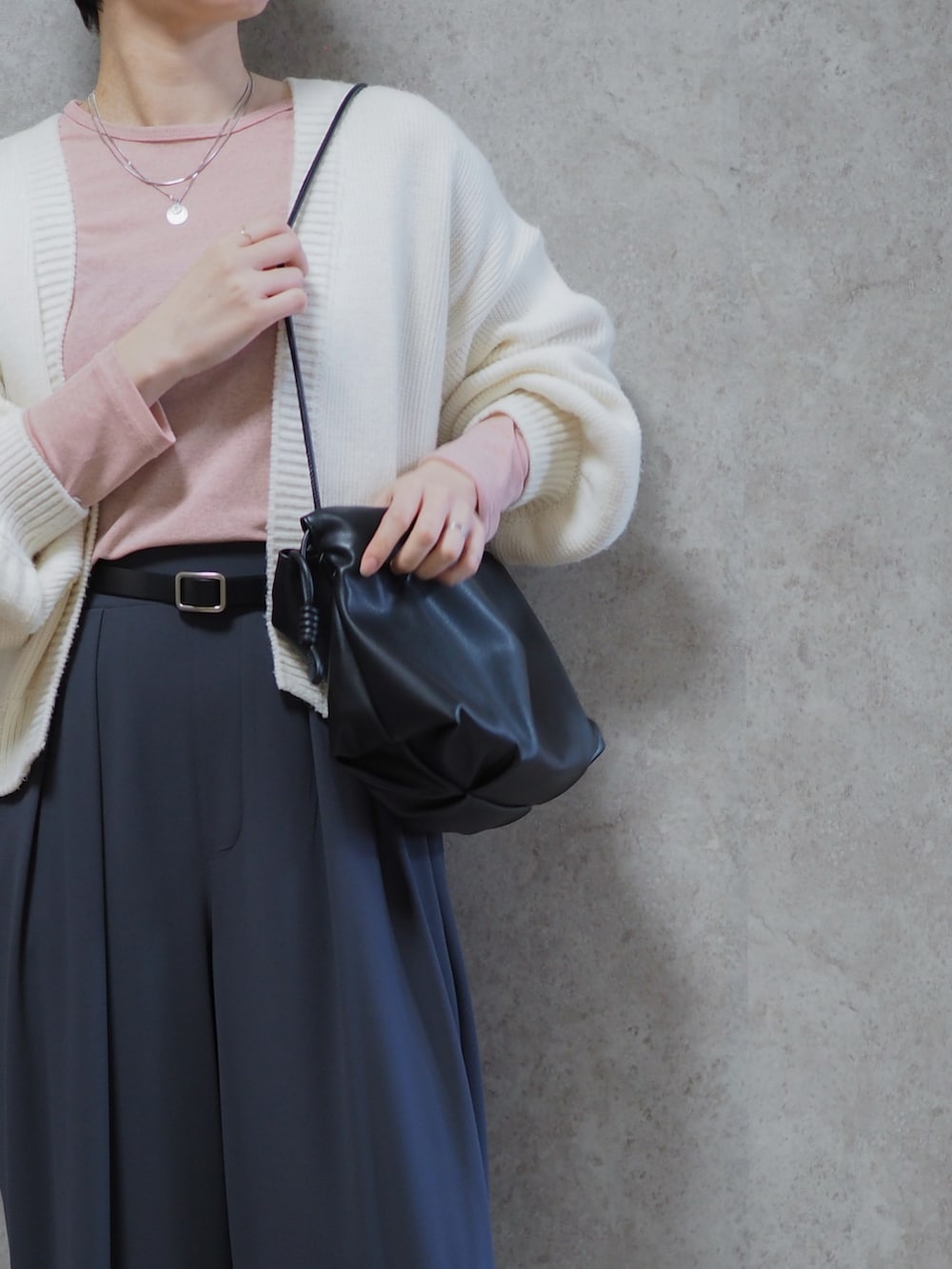 グレー系のスラックス、ブラック系のパンプス、ピンク系のTシャツ/カットソーを着用したレディースの春コーディネートの2枚目の写真