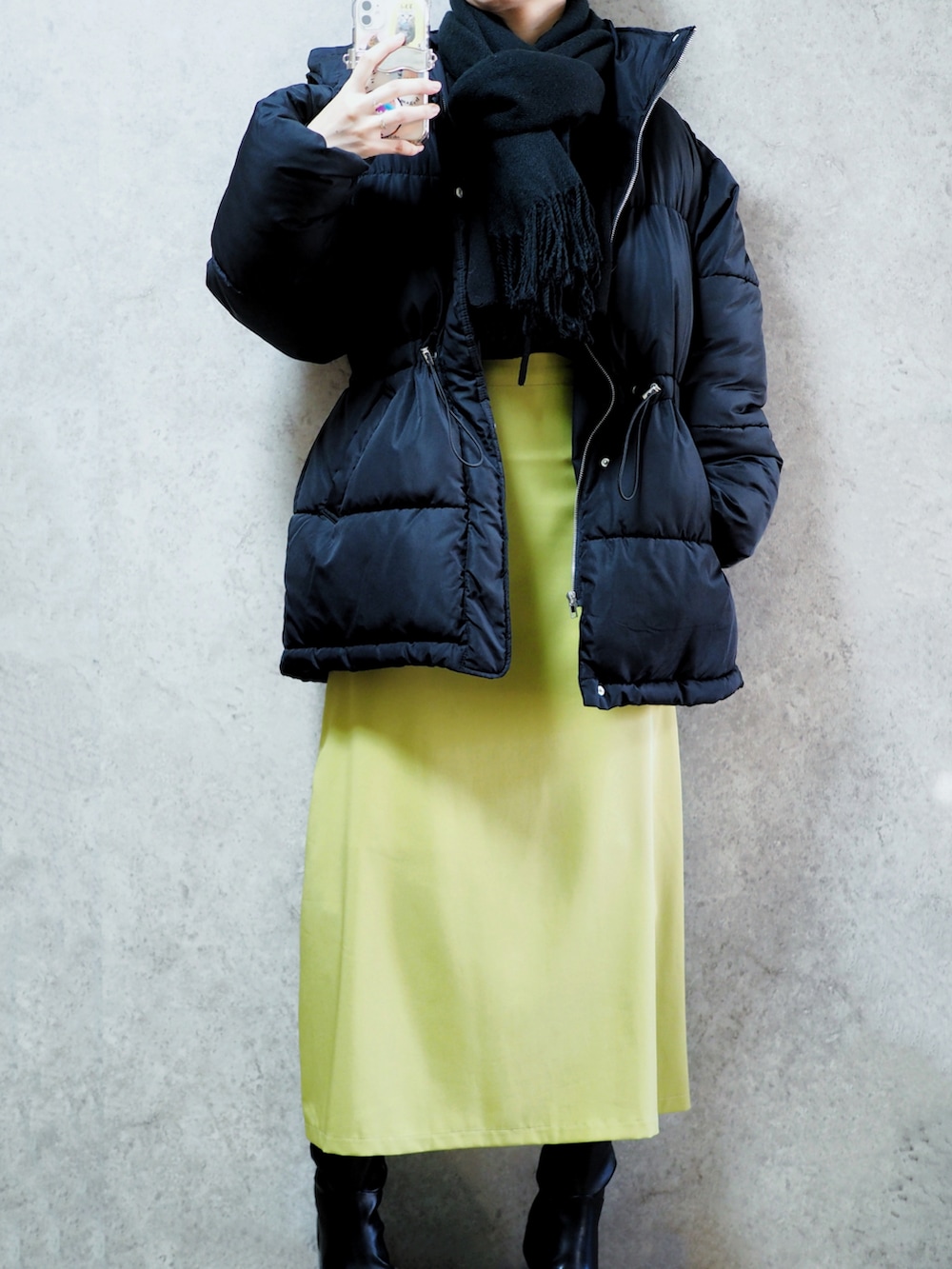 グリーン系のスカート、ブラック系のブーツ、ブラック系のニット/セーターを着用したレディースの冬コーディネートの2枚目の写真