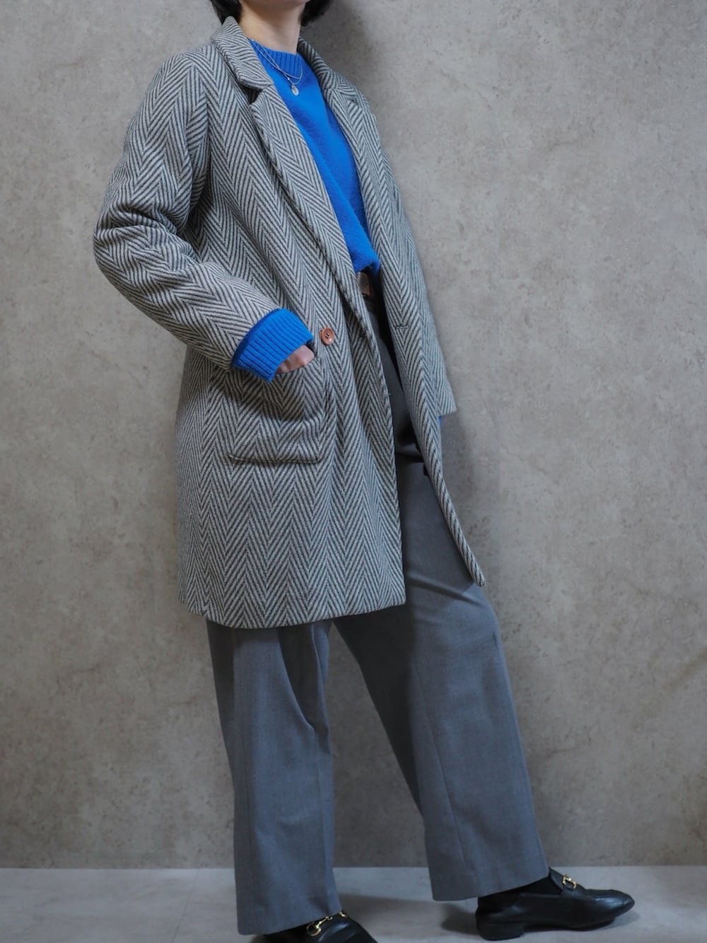 ブラック系のローファー、ブルー系のニット/セーター、グレー系のチェスターコートを着用したレディースの春コーディネートの2枚目の写真