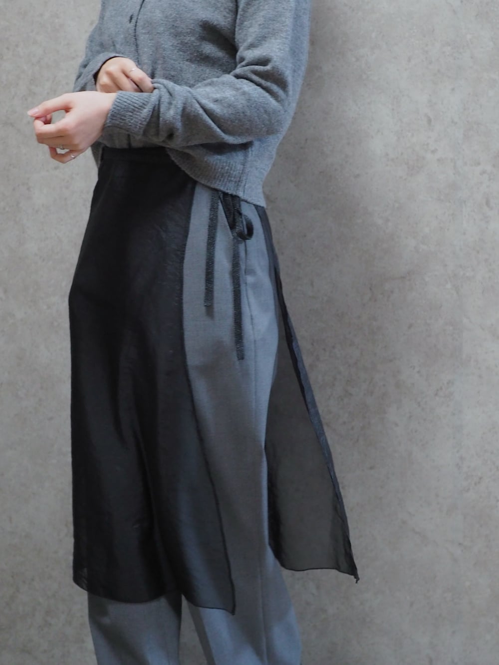 ブラック系のスカート、グレー系のカーディガン/ボレロ、グレー系のスラックスを着用したレディースの春コーディネートの2枚目の写真