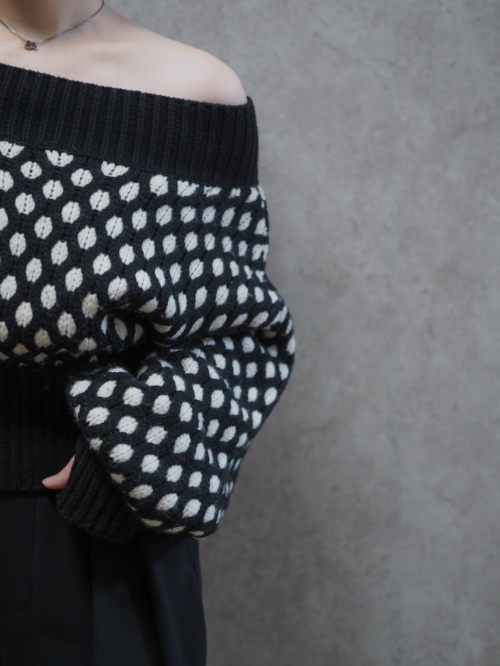 ブラック系のニット/セーター、ブラック系のスラックス、ブラック系のパンプスを着用したレディースの春コーディネートの2枚目の写真