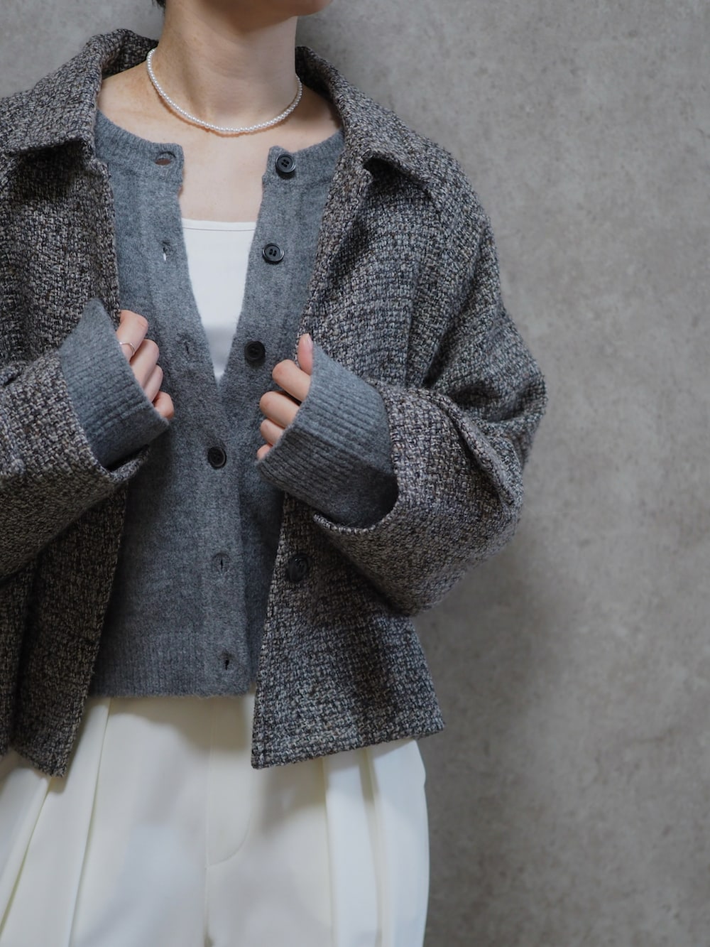 ホワイト系のスラックス、ブラック系のショルダーバッグ、グレー系のカーディガン/ボレロを着用したレディースの春コーディネートの2枚目の写真