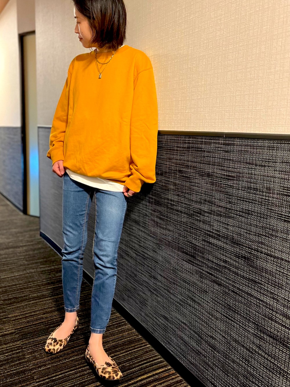 イエロー系のスウェット、ホワイト系のTシャツ/カットソー、ブルー系のデニムパンツを着用したレディースの秋コーディネートの2枚目の写真