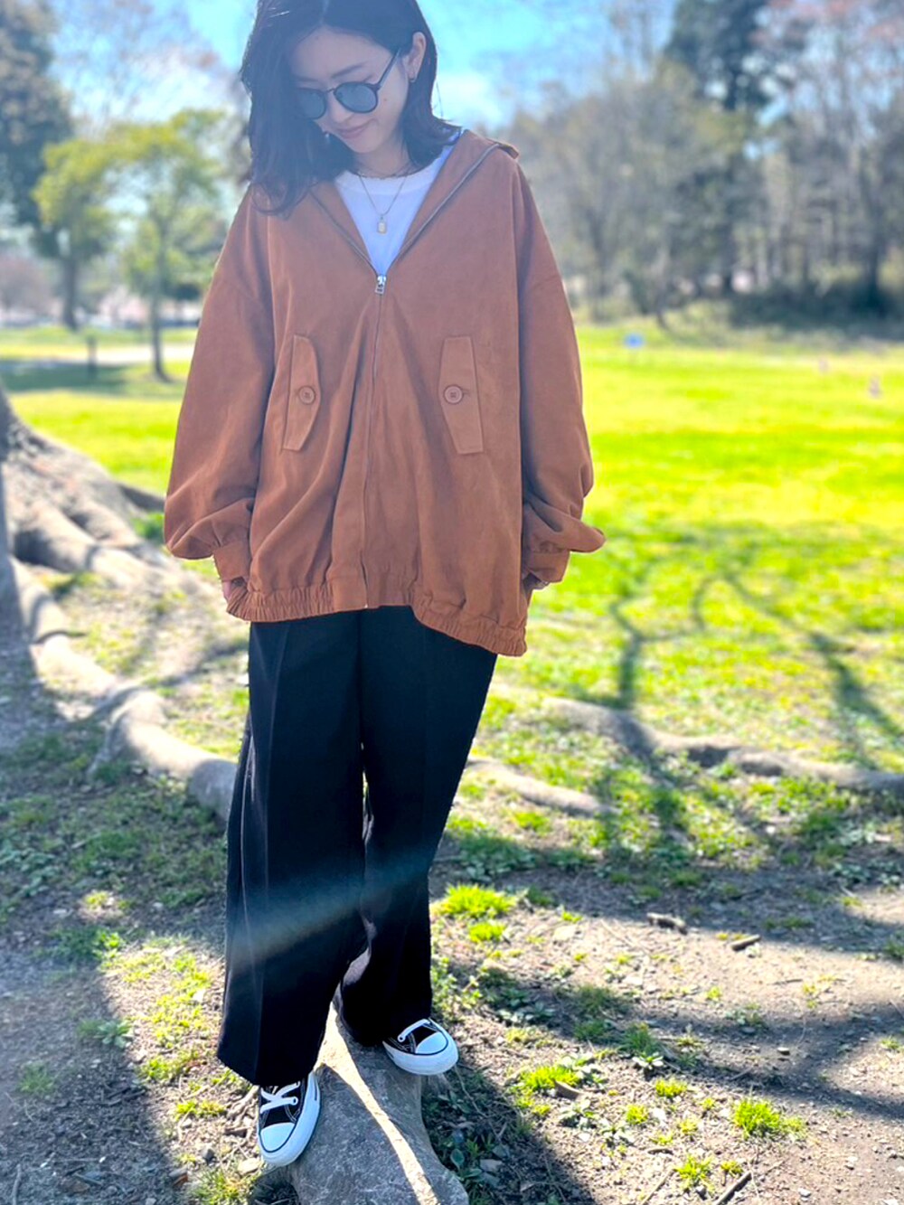 ブラック系のパンツ、ブラック系のスニーカー、オレンジ系のブルゾンを着用したレディースの春コーディネートの2枚目の写真