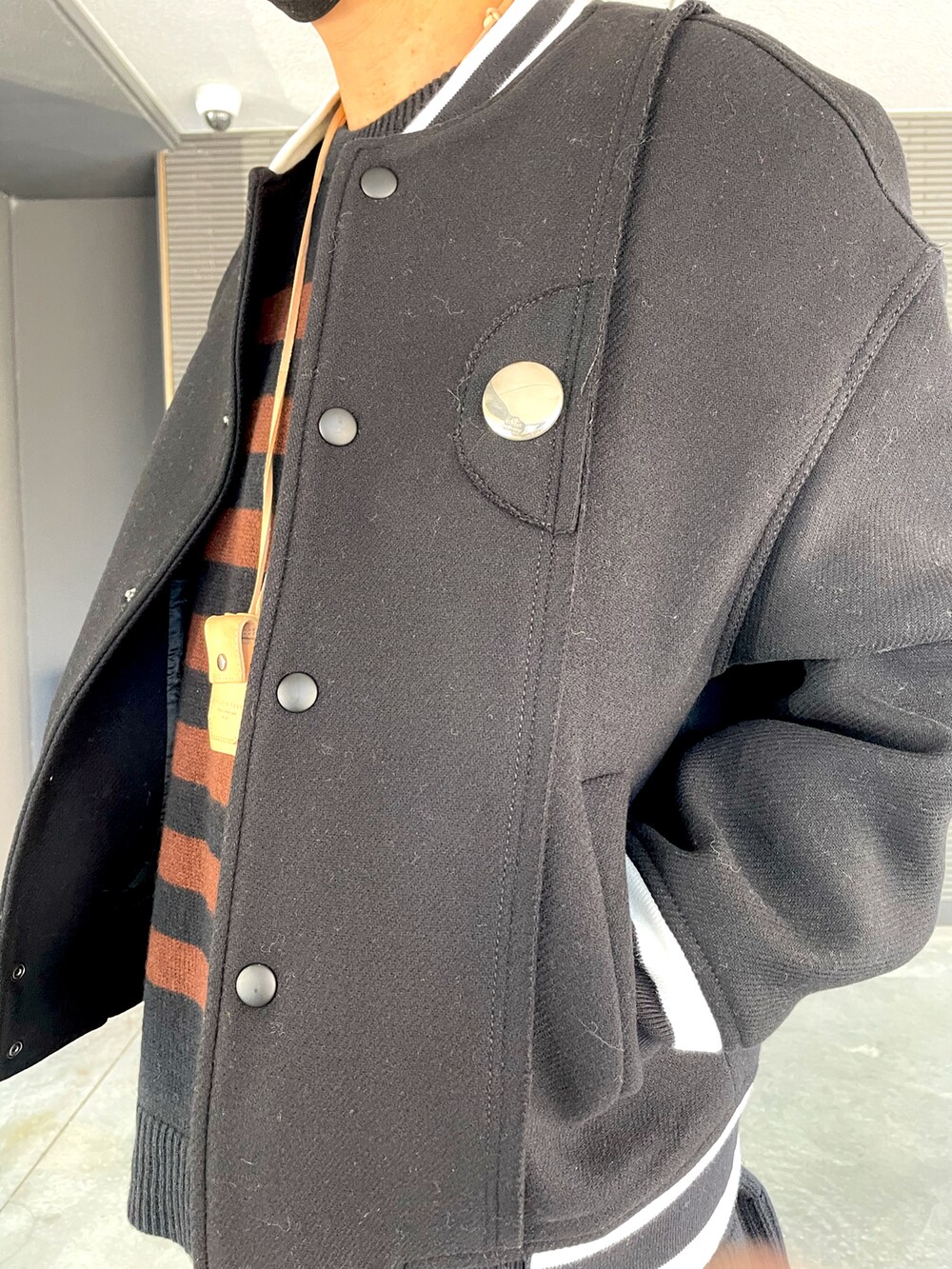 ブラック系のスタジャン、ブラウン系のニット/セーター、シルバー系のブローチ/コサージュを着用したメンズの冬コーディネートの4枚目の写真