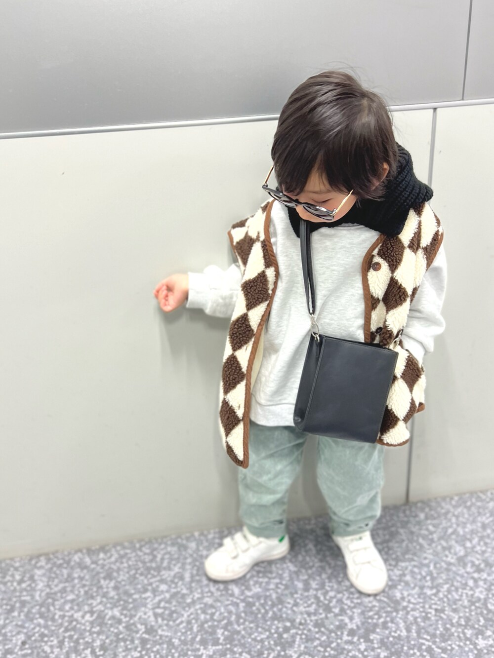 ホワイト系のスニーカー、ベージュ系のベスト、グレー系のスウェットを着用したキッズの冬コーディネートの3枚目の写真