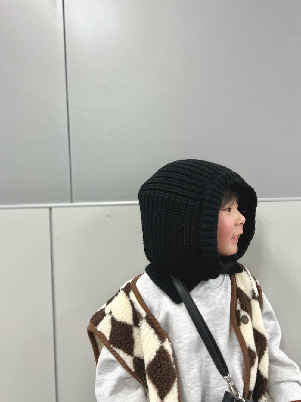 ホワイト系のスニーカー、ベージュ系のベスト、グレー系のスウェットを着用したキッズの冬コーディネートの2枚目の写真