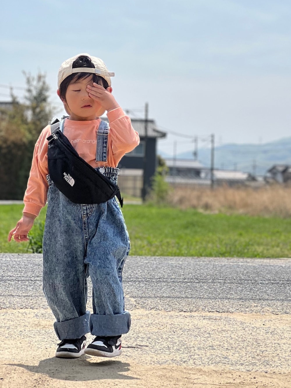 ホワイト系のスニーカー、ブラック系のボディバッグ/ウエストポーチ、ブルー系のオールインワン・サロペットを着用したキッズの春コーディネートの2枚目の写真