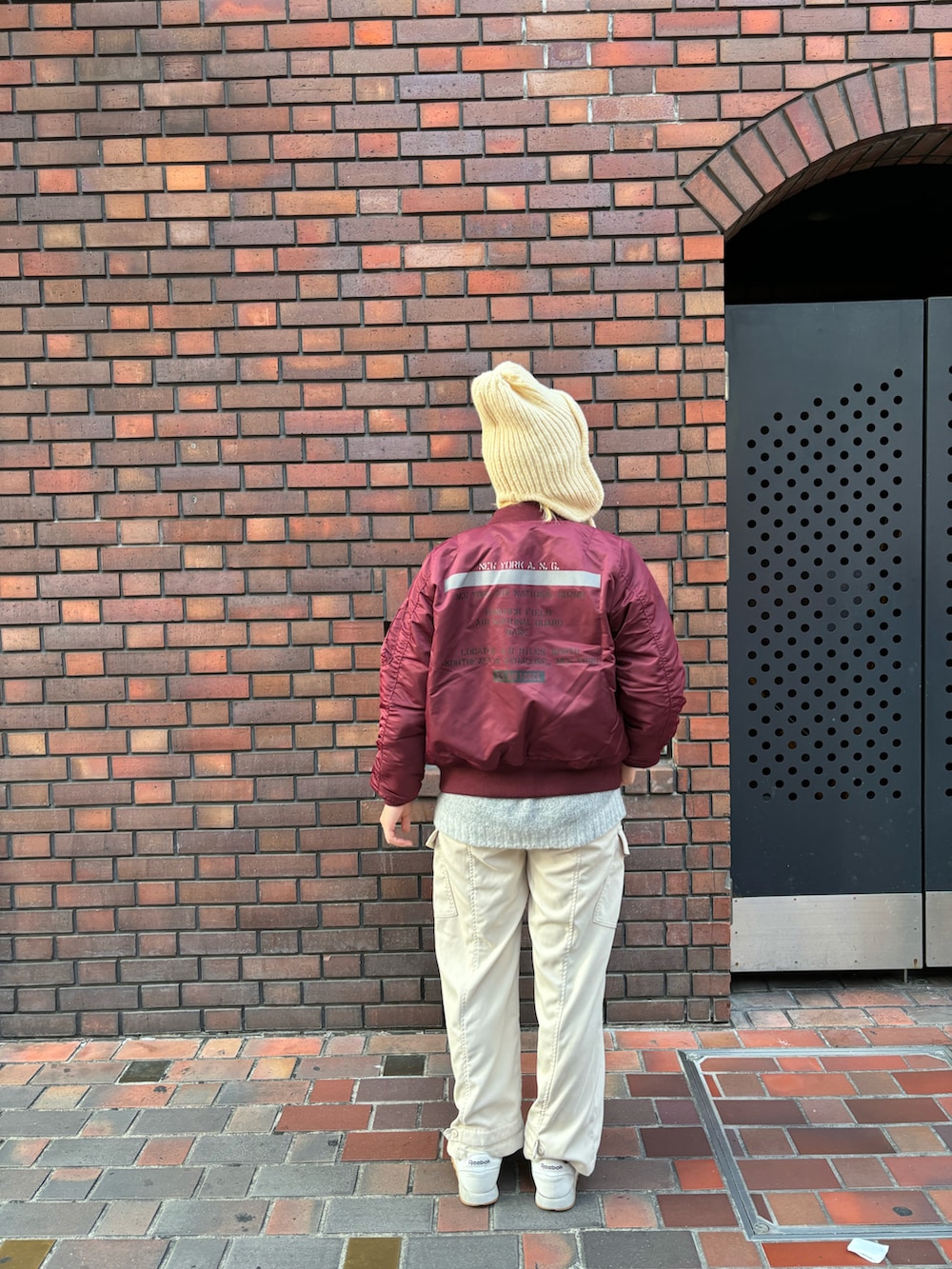 レッド系のMA-1、グレー系のニット/セーター、ホワイト系のカーゴパンツを着用したレディースの秋コーディネートの2枚目の写真