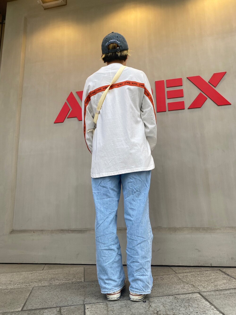 ホワイト系のショルダーバッグ、ホワイト系のTシャツ/カットソー、ブルー系のキャップを着用したレディースの春コーディネートの2枚目の写真