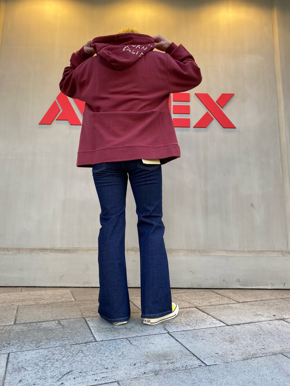 レッド系のパーカー、その他のデニムパンツを着用したレディースの冬コーディネートの3枚目の写真