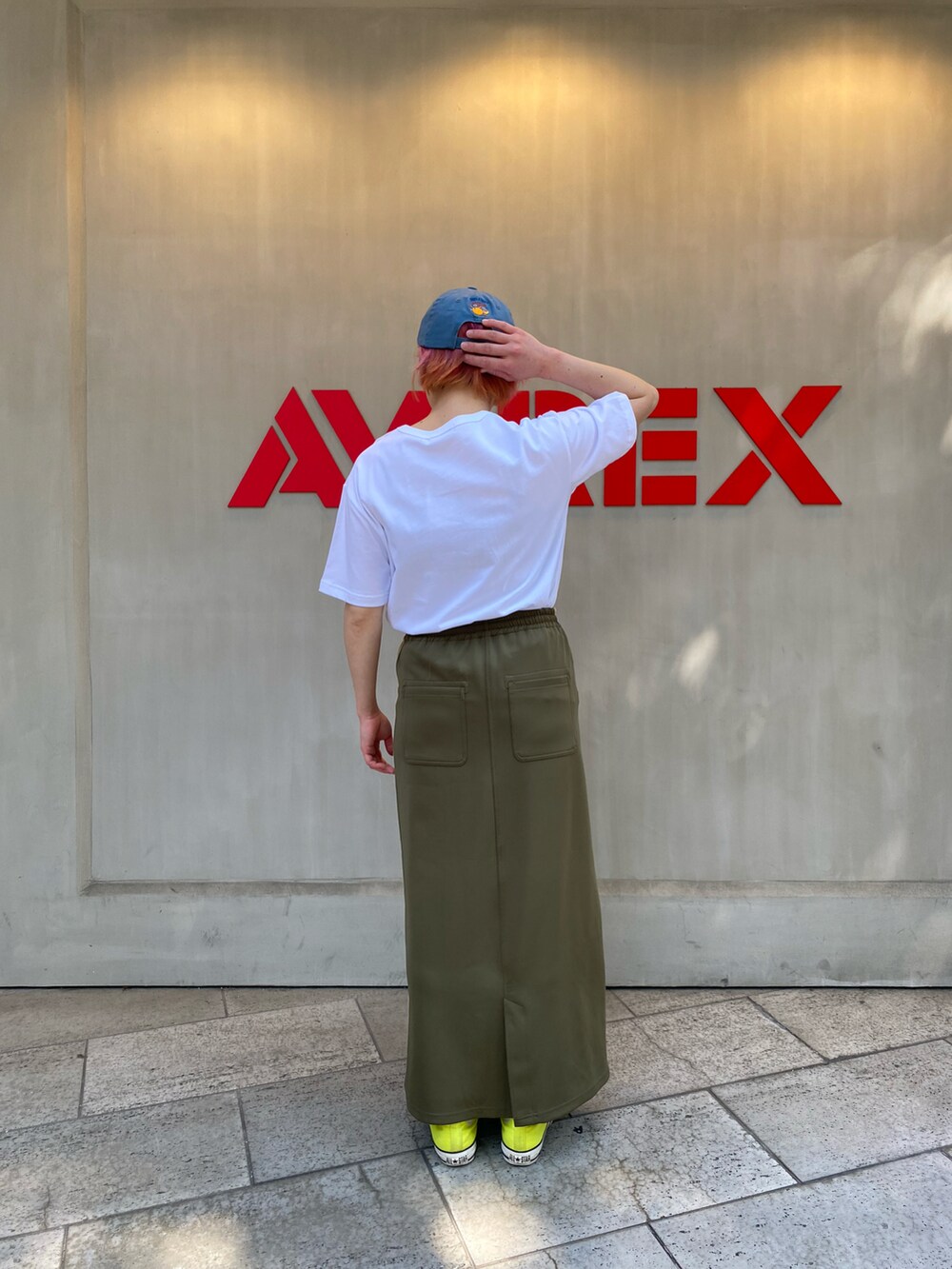 ホワイト系のTシャツ/カットソー、グリーン系のスカート、ブルー系のキャップを着用したレディースの春コーディネートの2枚目の写真