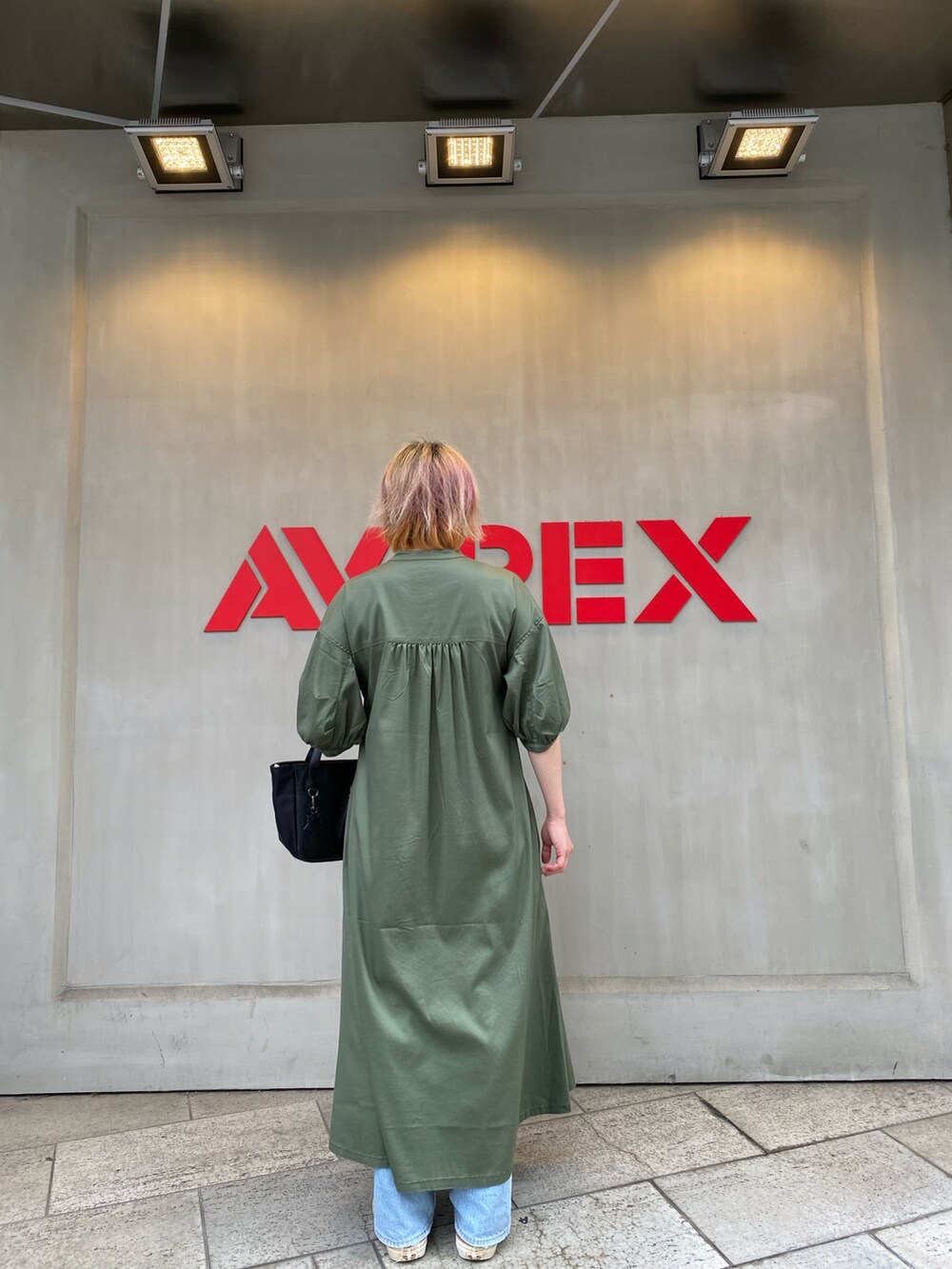 グリーン系のワンピース、ブラック系のトートバッグを着用したレディースの夏コーディネートの2枚目の写真