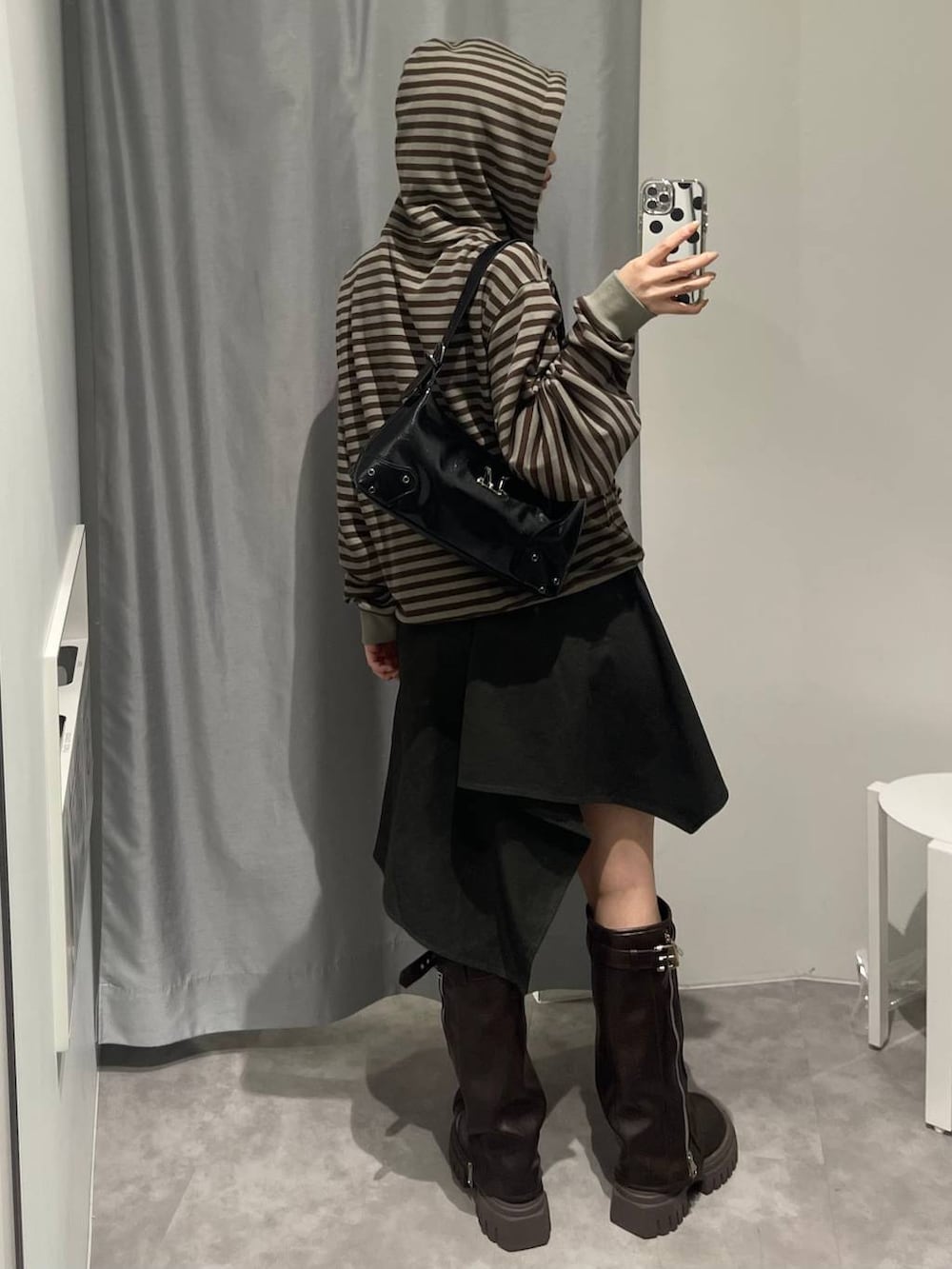 ブラウン系のブーツ、グリーン系のスカート、ブラック系のハンドバッグを着用したレディースの秋コーディネートの4枚目の写真