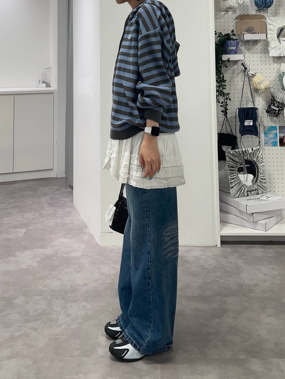 ブルー系のデニムパンツ、ブルー系のパーカー、ホワイト系のスカートを着用したレディースの夏コーディネートの5枚目の写真