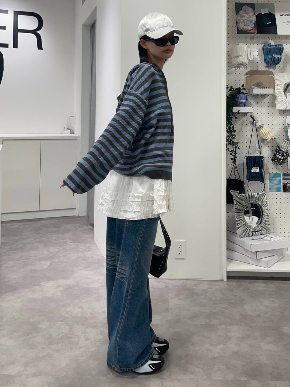 ブルー系のデニムパンツ、ブルー系のパーカー、ホワイト系のスカートを着用したレディースの夏コーディネートの2枚目の写真