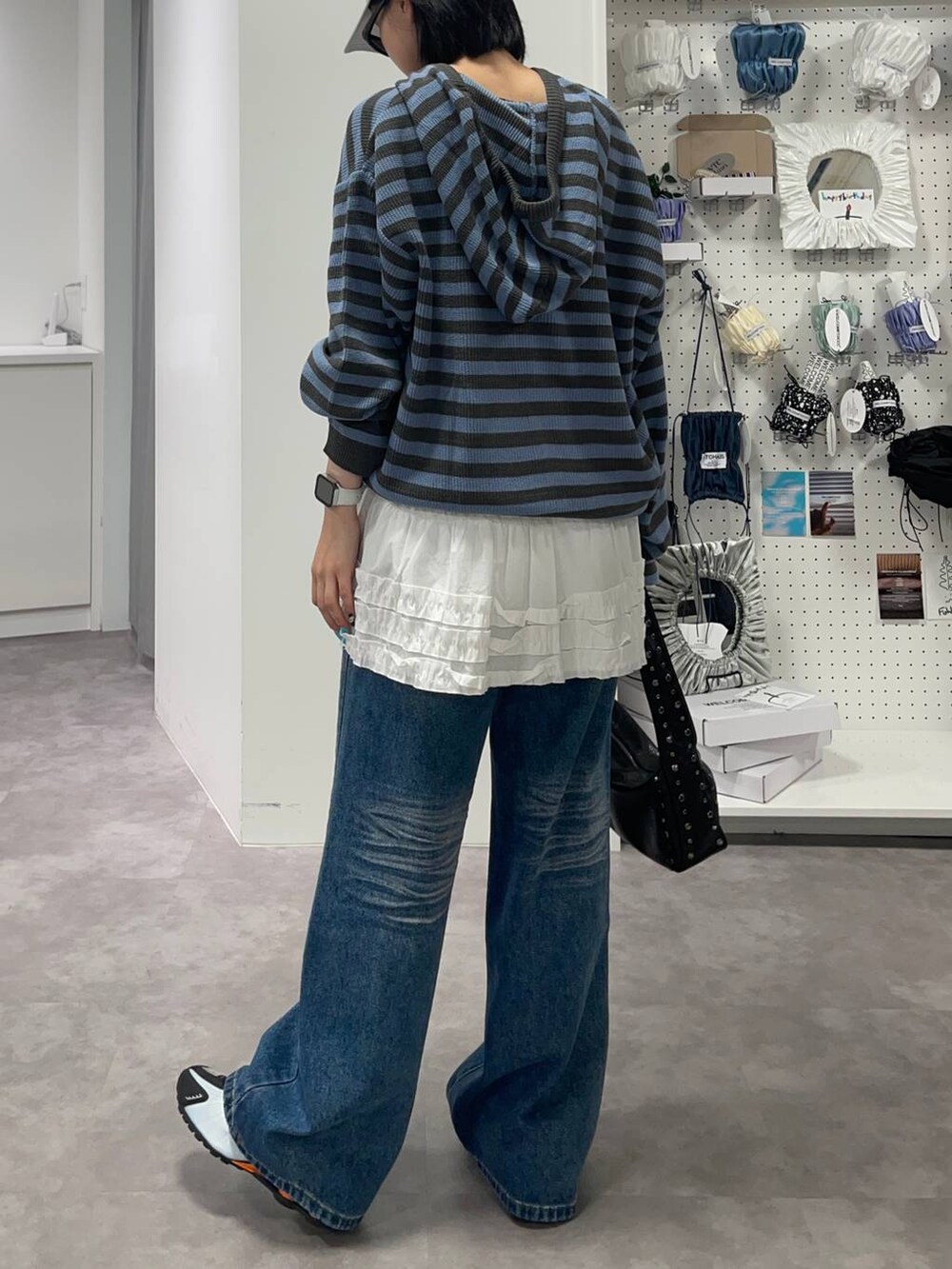 ブルー系のデニムパンツ、ブルー系のパーカー、ホワイト系のスカートを着用したレディースの夏コーディネートの4枚目の写真