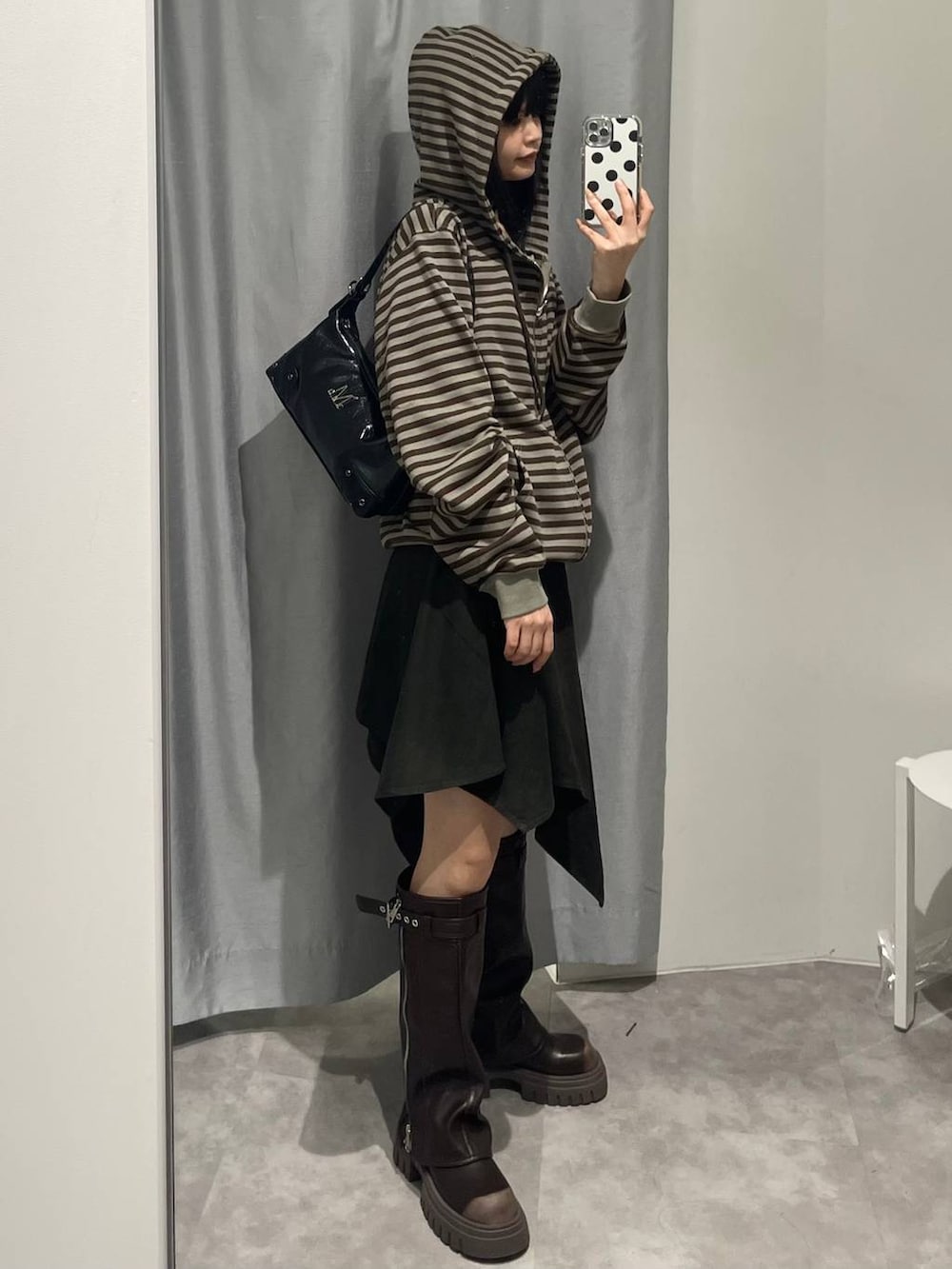 ブラウン系のブーツ、グリーン系のスカート、ブラック系のハンドバッグを着用したレディースの秋コーディネートの3枚目の写真