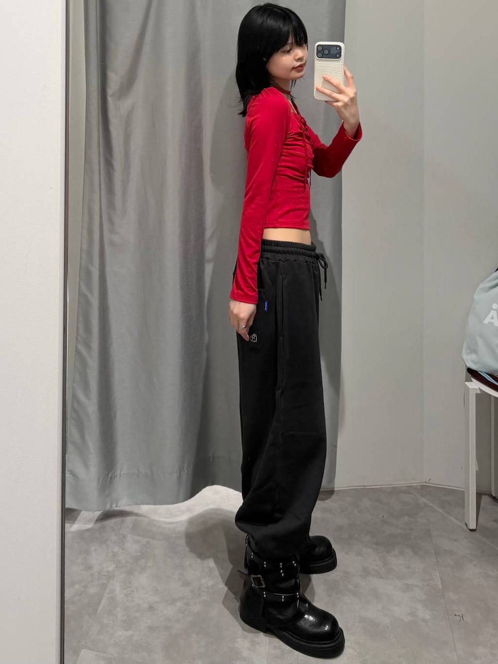 レッド系のTシャツ/カットソー、ブラック系のスウェットパンツ、ブラック系のブーツを着用したレディースの冬コーディネートの3枚目の写真