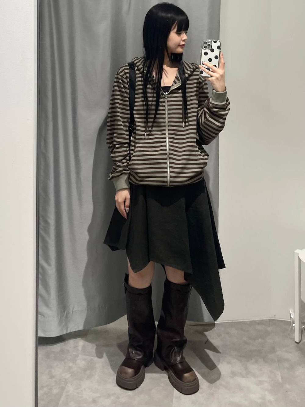 ブラウン系のブーツ、グリーン系のスカート、ブラック系のハンドバッグを着用したレディースの秋コーディネートの2枚目の写真