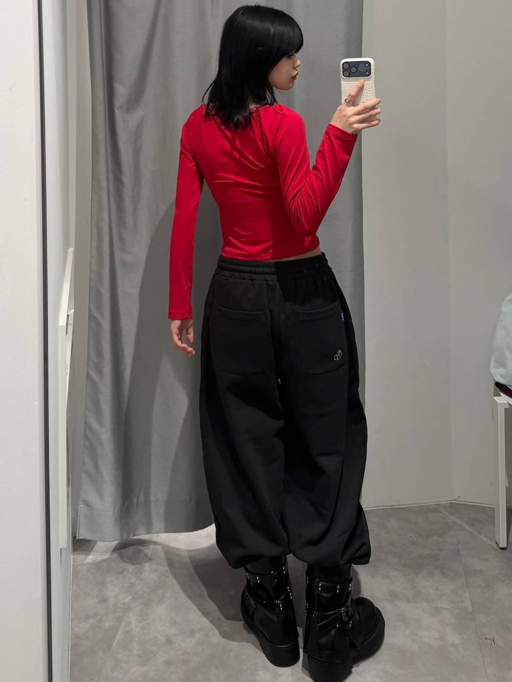 レッド系のTシャツ/カットソー、ブラック系のスウェットパンツ、ブラック系のブーツを着用したレディースの冬コーディネートの4枚目の写真