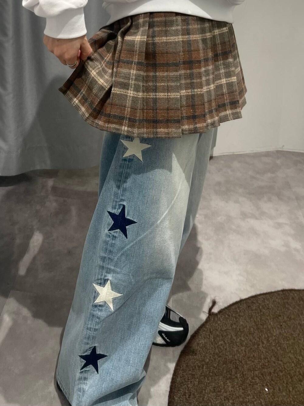 ブルー系のデニムパンツ、ブラウン系のスカート、ベージュ系のパーカーを着用したレディースの秋コーディネートの5枚目の写真