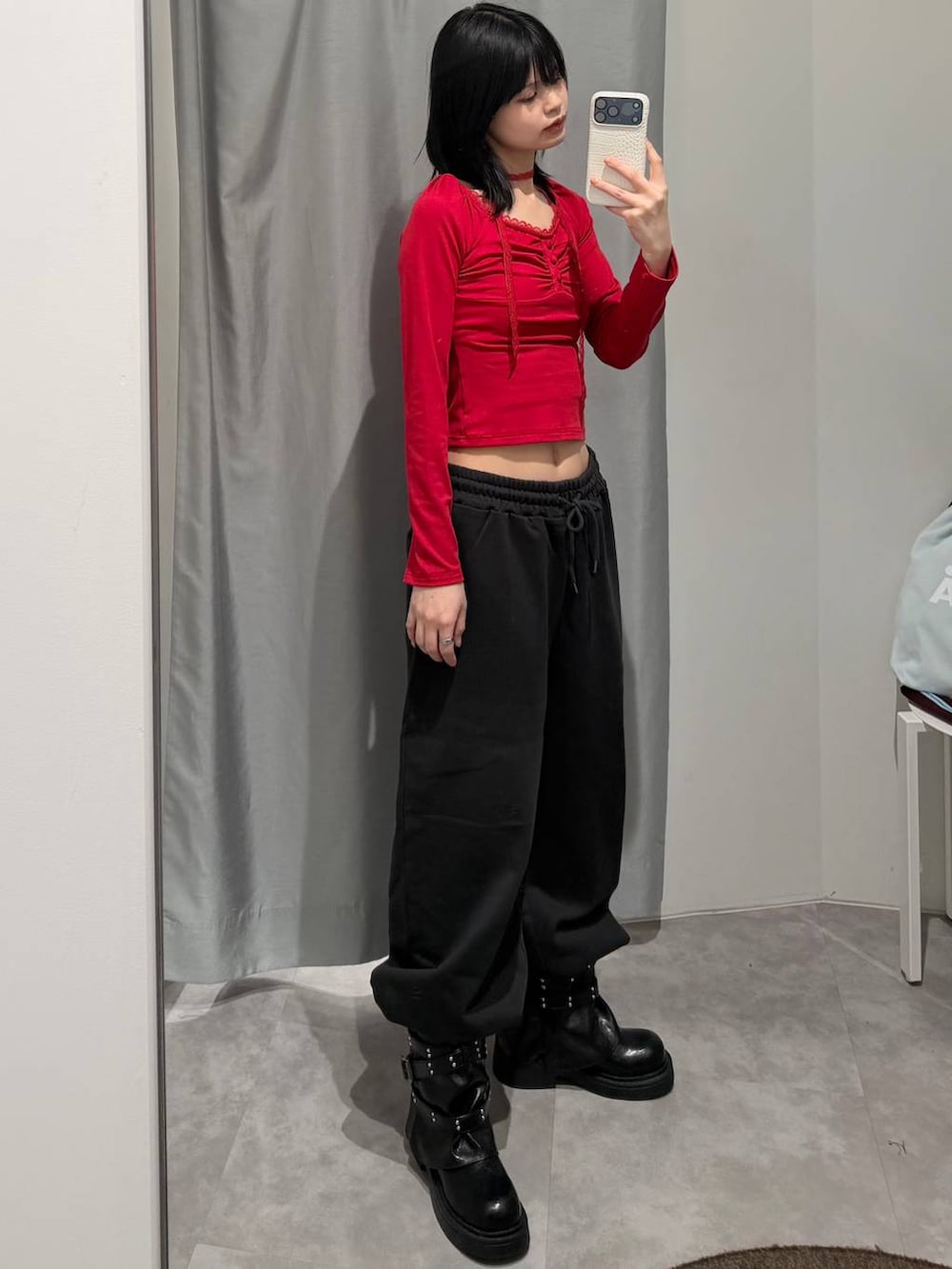 レッド系のTシャツ/カットソー、ブラック系のスウェットパンツ、ブラック系のブーツを着用したレディースの冬コーディネートの2枚目の写真