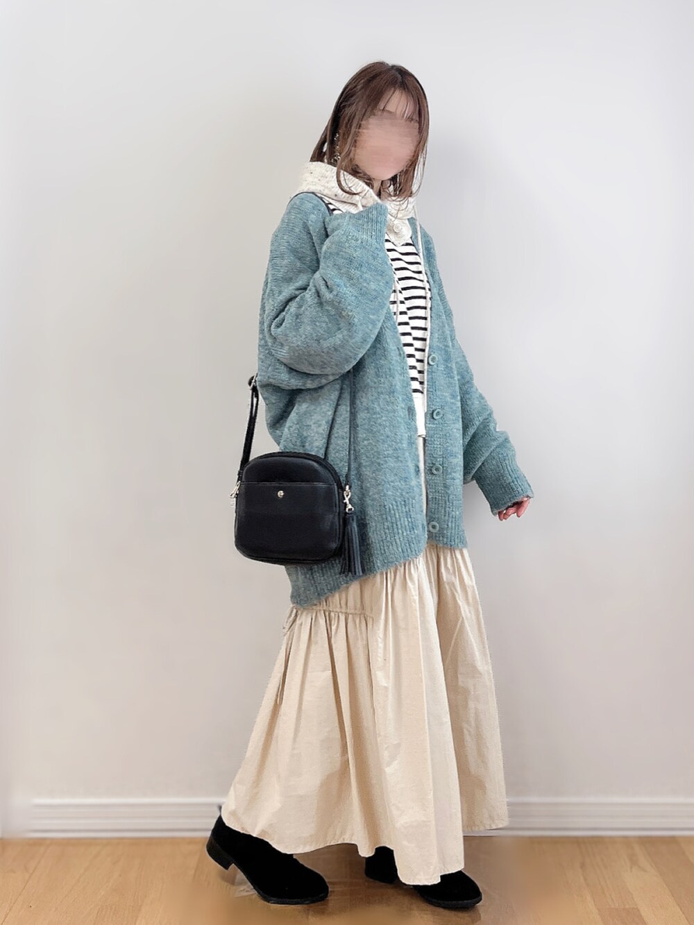 グリーン系のカーディガン/ボレロ、ブラック系のスウェット、ホワイト系のスカートを着用したレディースの冬コーディネートの3枚目の写真