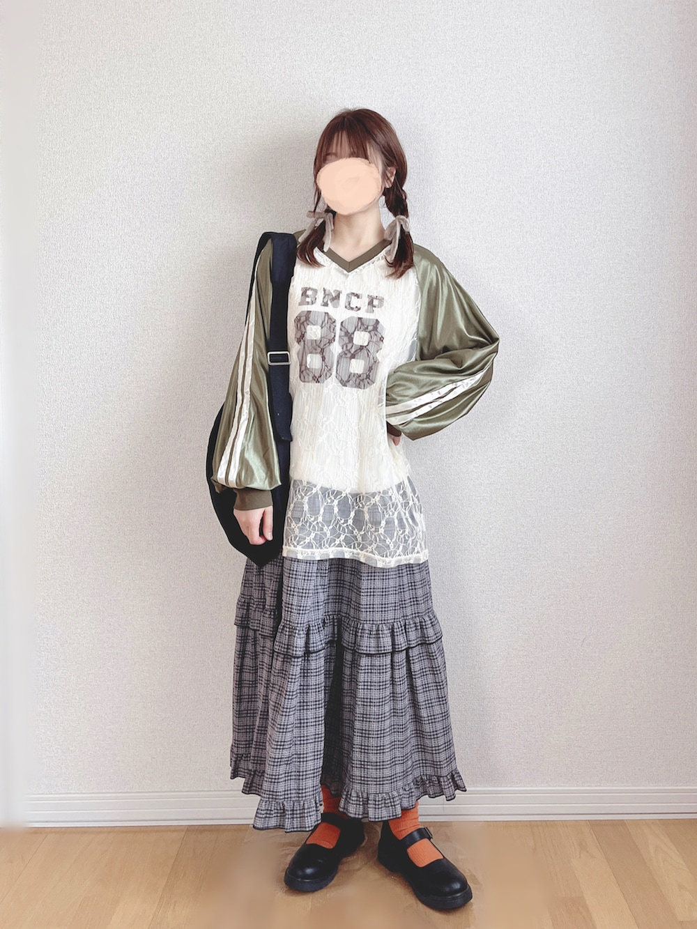 グリーン系のTシャツ/カットソー、グレー系のスカート、ブラック系のショルダーバッグを着用したレディースの冬コーディネートの2枚目の写真