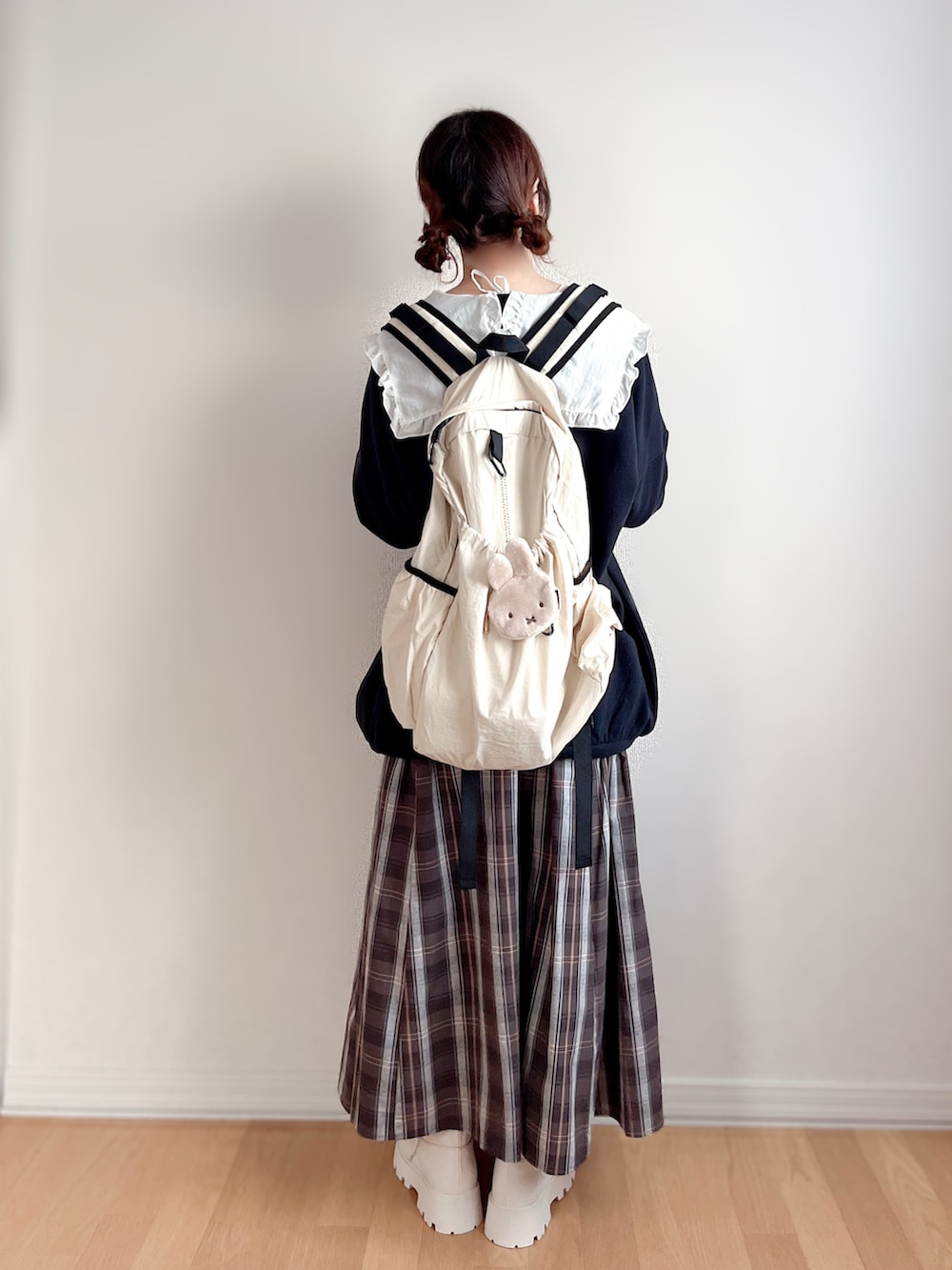 ホワイト系のシャツ/ブラウス、ホワイト系のブーツ、ベージュ系のバックパック/リュックを着用したレディースの冬コーディネートの3枚目の写真