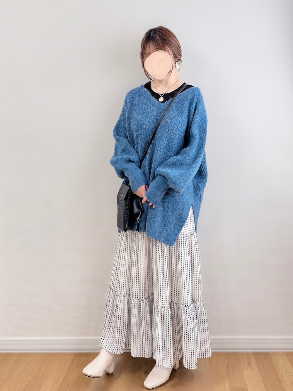 ブルー系のニット/セーター、ブラック系のTシャツ/カットソー、ホワイト系のスカートを着用したレディースの冬コーディネートの2枚目の写真