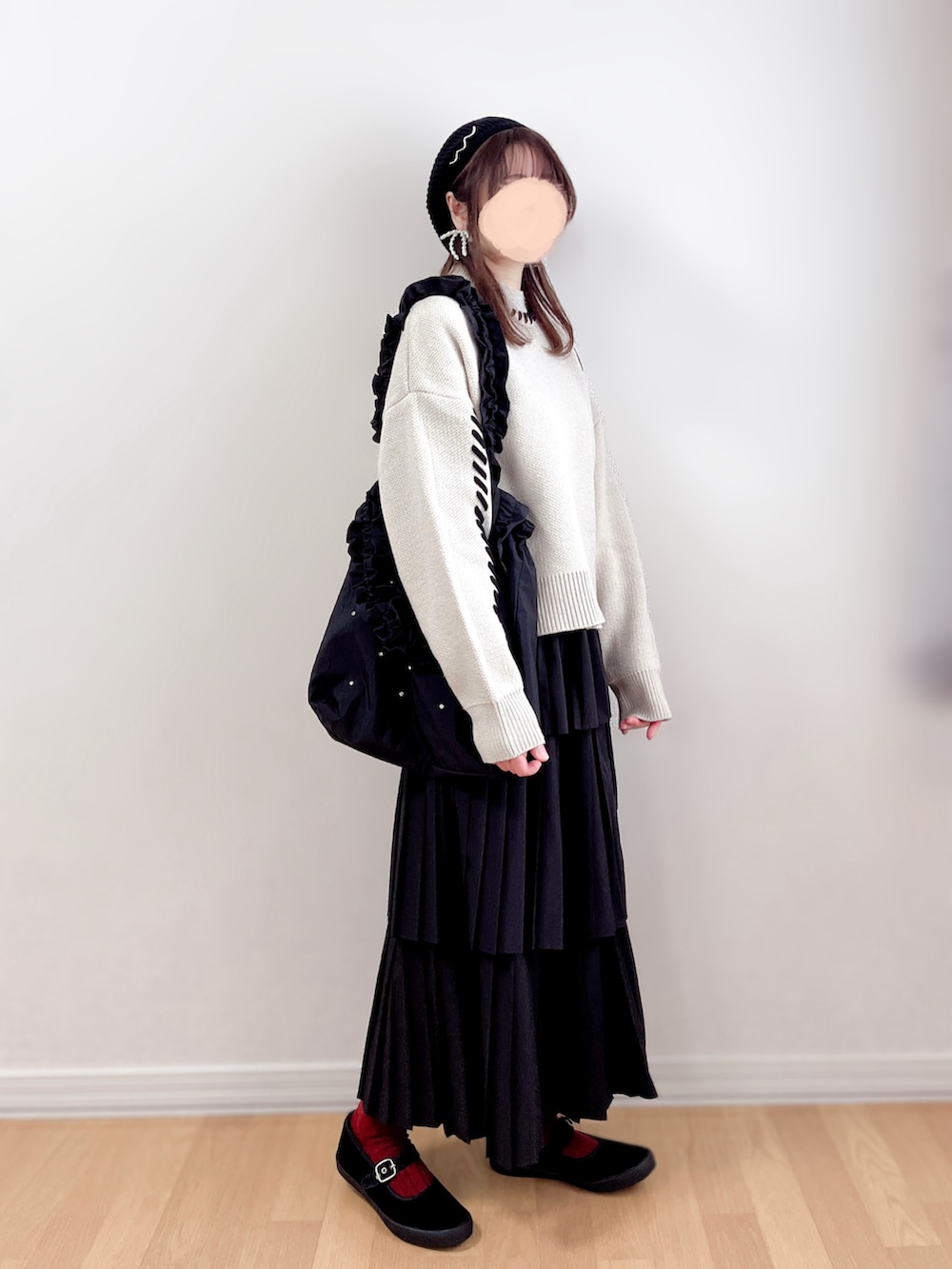 ベージュ系のニット/セーター、ブラック系のスカート、ブラック系のトートバッグを着用したレディースの春コーディネートの2枚目の写真