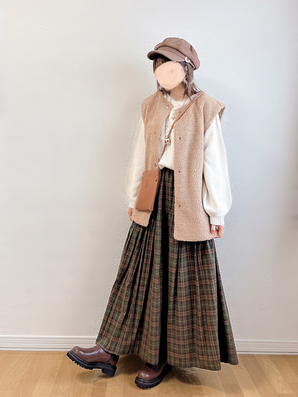 ホワイト系のニット/セーター、ベージュ系のベスト、ブラウン系のスカートを着用したレディースの秋コーディネートの2枚目の写真