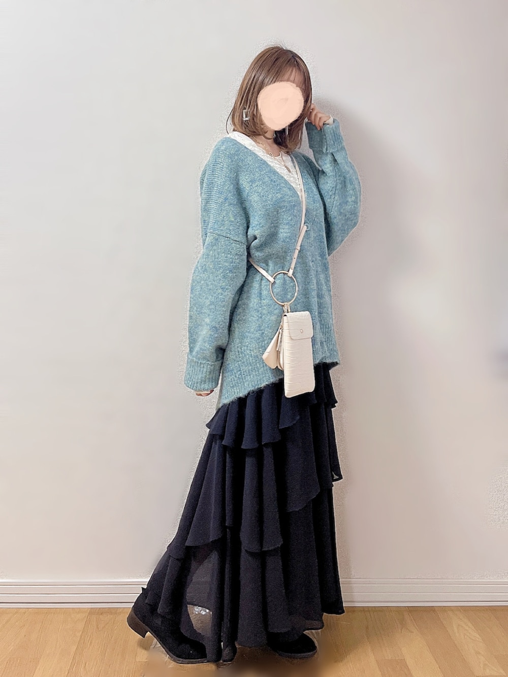 グリーン系のカーディガン/ボレロ、ホワイト系のTシャツ/カットソー、ブラック系のスカートを着用したレディースの冬コーディネートの3枚目の写真