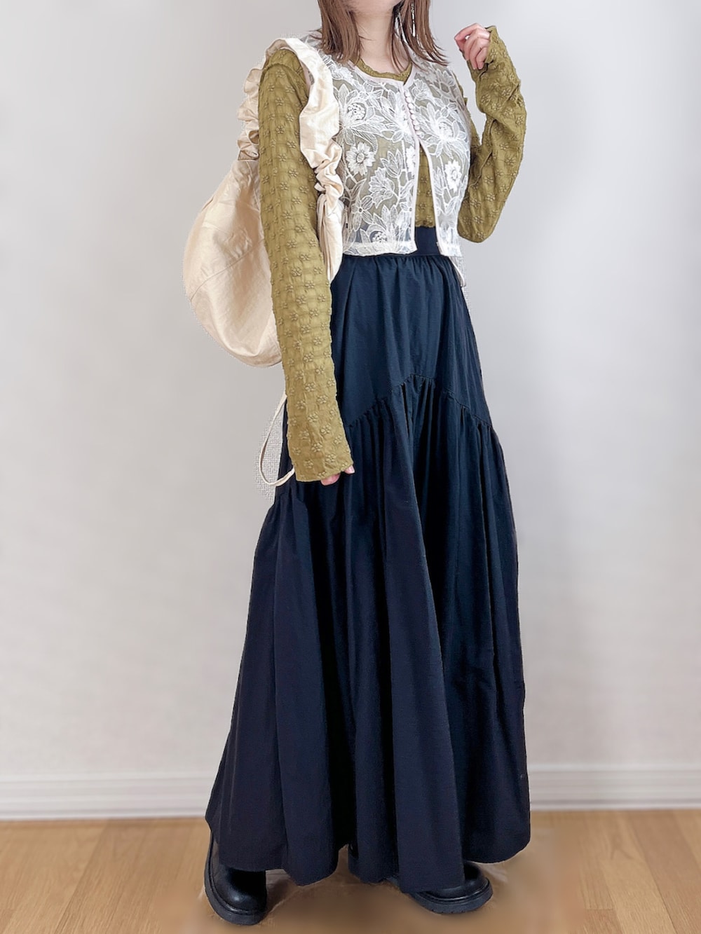 ホワイト系のベスト、グリーン系のTシャツ/カットソー、ブラック系のスカートを着用したレディースの春コーディネートの3枚目の写真