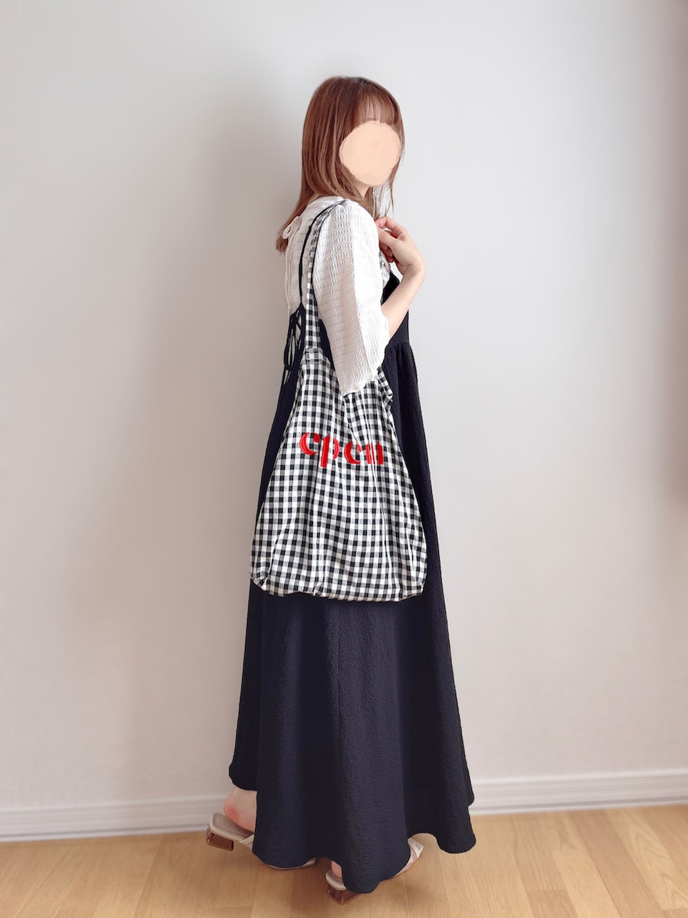 ブラック系のワンピース、ブラック系のトートバッグ、ベージュ系のサンダルを着用したレディースの夏コーディネートの3枚目の写真