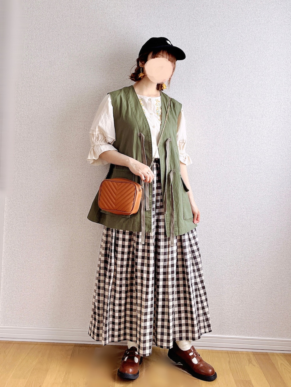 グリーン系のベスト、ホワイト系のシャツ/ブラウス、ブラック系のスカートを着用したレディースの夏コーディネートの3枚目の写真