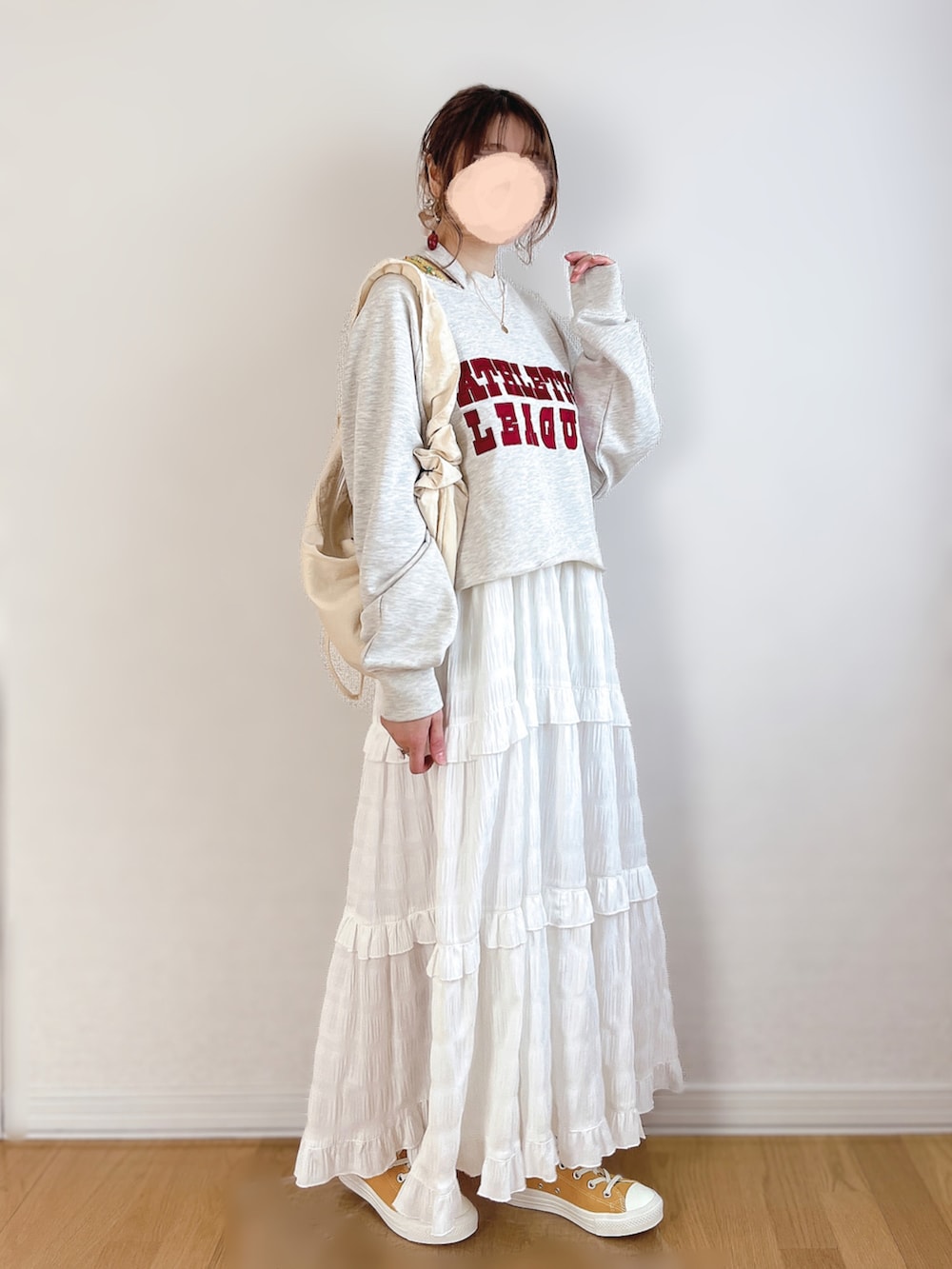 グレー系のスウェット、ホワイト系のワンピース、ゴールド系のスニーカーを着用したレディースの春コーディネートの2枚目の写真