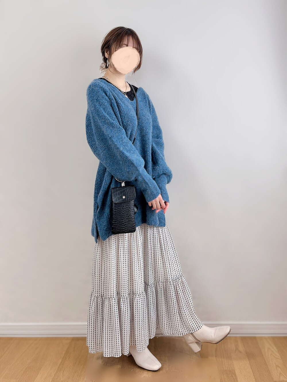 ブルー系のニット/セーター、ブラック系のTシャツ/カットソー、ホワイト系のスカートを着用したレディースの冬コーディネートの3枚目の写真