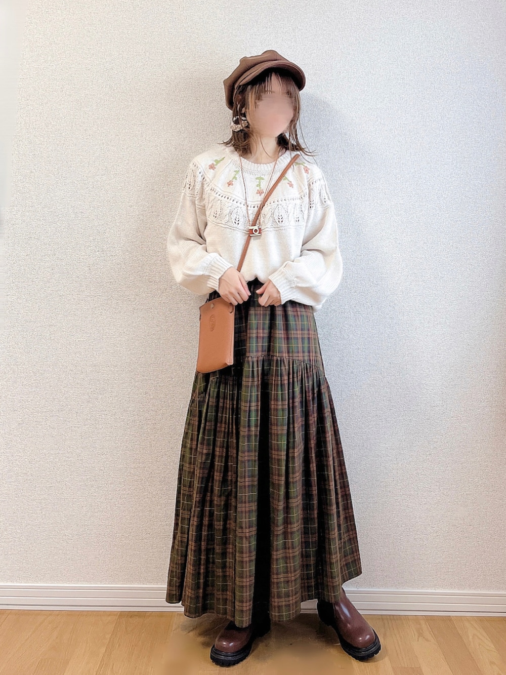 ホワイト系のニット/セーター、ブラウン系のスカート、ブラウン系のブーツを着用したレディースの秋コーディネートの2枚目の写真