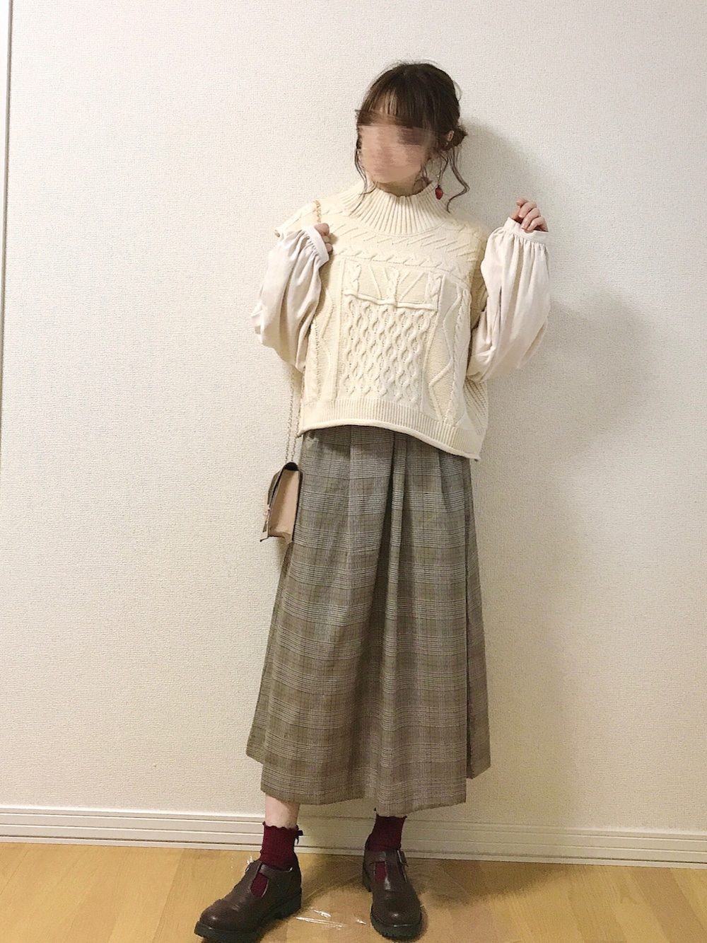 ブラウン系のノーカラーコート、ベージュ系のベスト、ブラウン系のスカートを着用したレディースの冬コーディネートの5枚目の写真