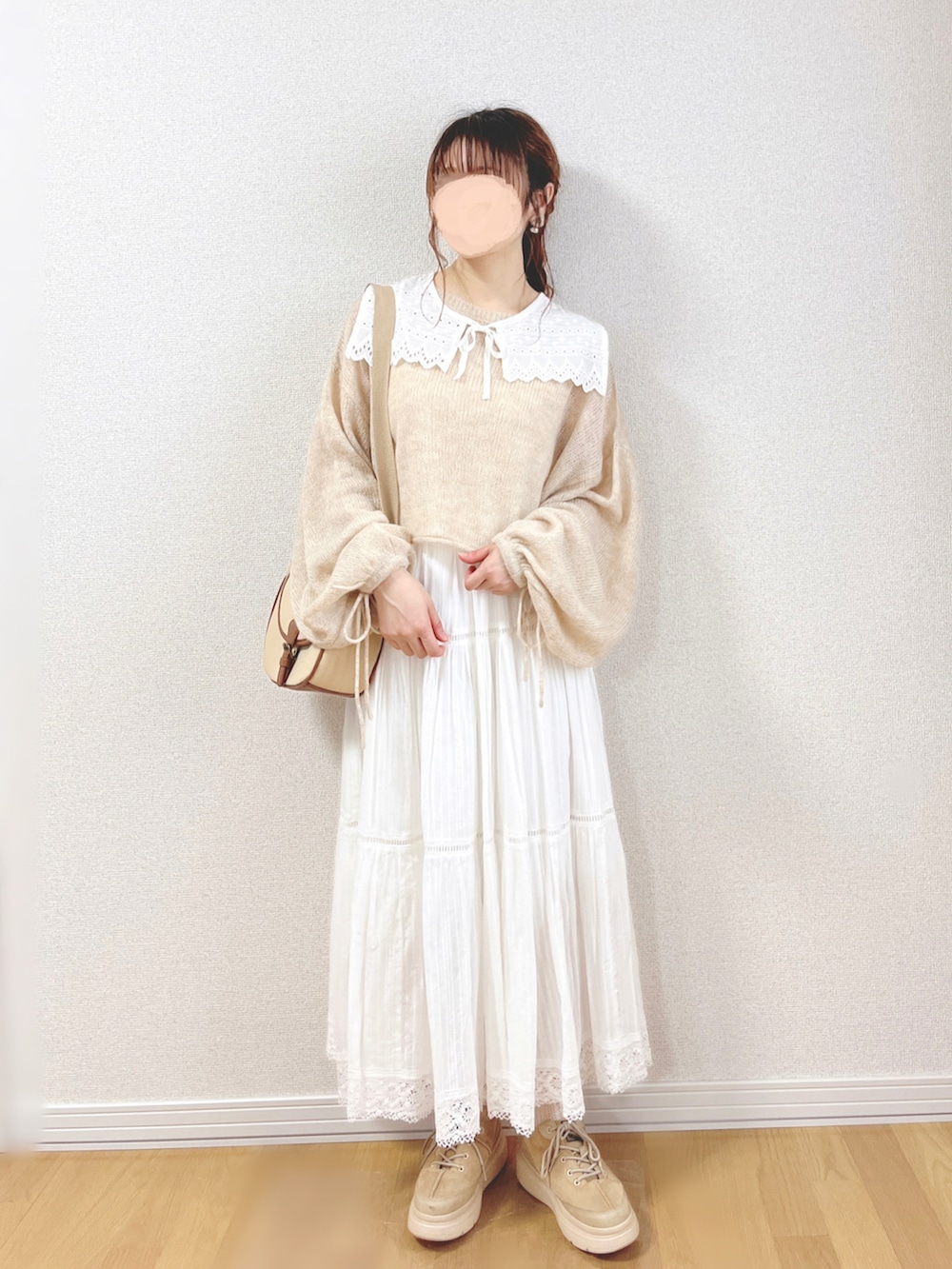 ベージュ系のニット/セーター、ホワイト系のスカート、ベージュ系のショルダーバッグを着用したレディースの秋コーディネートの2枚目の写真