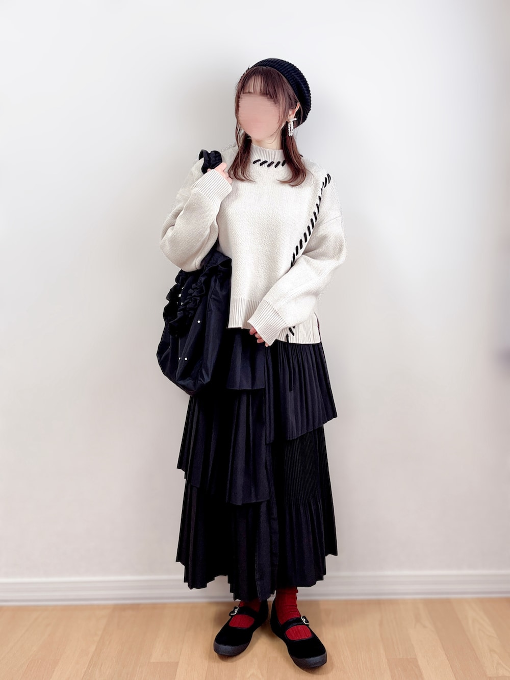 ベージュ系のニット/セーター、ブラック系のスカート、ブラック系のトートバッグを着用したレディースの春コーディネートの3枚目の写真