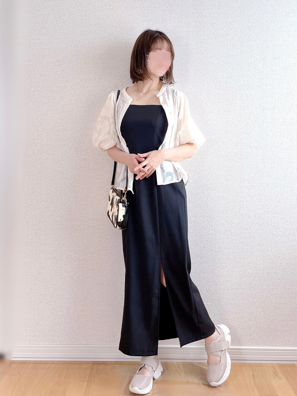 ブラック系のワンピース、ベージュ系のスニーカー、ホワイト系のショルダーバッグを着用したレディースの夏コーディネートの2枚目の写真