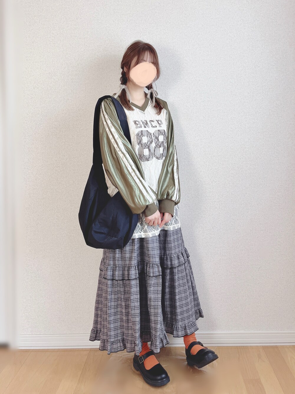 グリーン系のTシャツ/カットソー、グレー系のスカート、ブラック系のショルダーバッグを着用したレディースの冬コーディネートの3枚目の写真