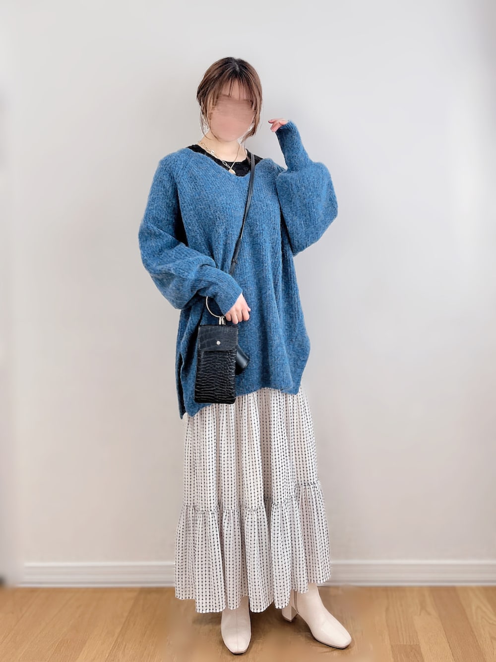 ブルー系のニット/セーター、ブラック系のTシャツ/カットソー、ホワイト系のスカートを着用したレディースの冬コーディネートの4枚目の写真