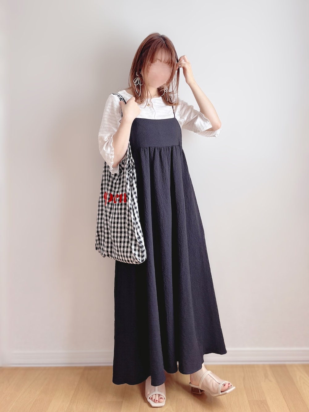 ブラック系のワンピース、ブラック系のトートバッグ、ベージュ系のサンダルを着用したレディースの夏コーディネートの2枚目の写真